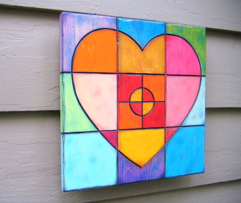 May include: A colorful heart-shaped mosaic made of square tiles in shades of blue, green, orange, pink, red, and purple. The tiles are arranged in a geometric pattern to create a heart shape.