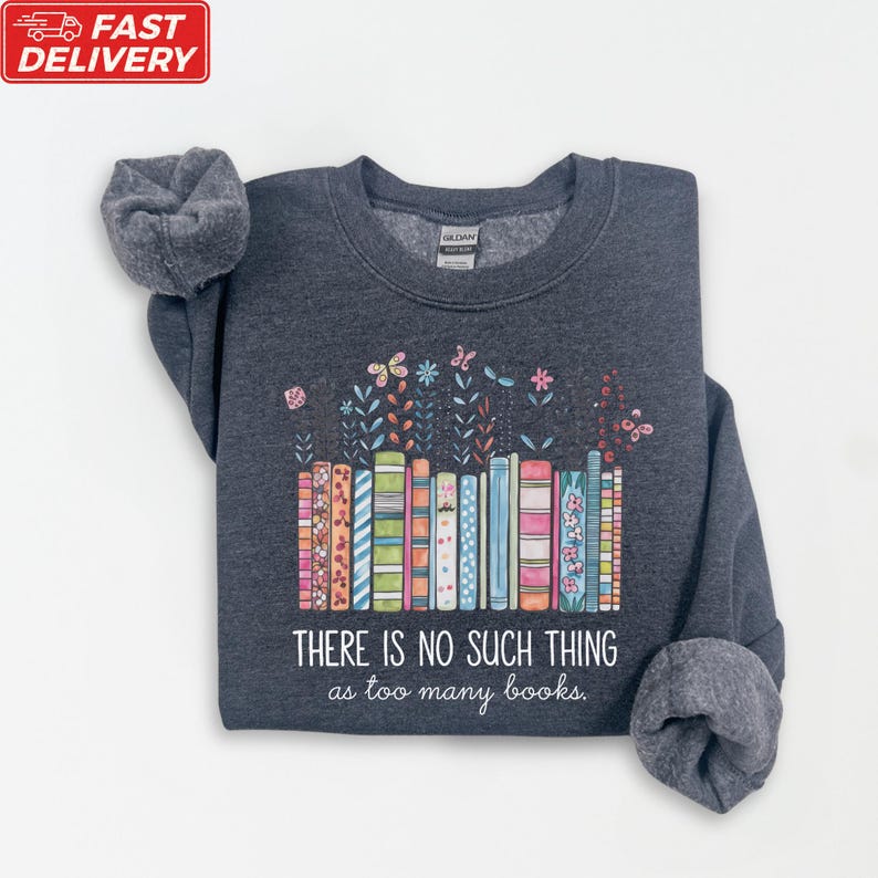 A gray sweatshirt with a colorful graphic design depicting a row of books and flowers, along with the text "THERE IS NO SUCH THING as too many books" printed on it.
