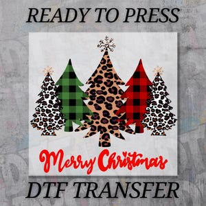 May include: A square DTF transfer design featuring five Christmas trees. The trees have various patterns, including leopard print, green plaid, and red plaid. The words "Merry Christmas" are in red script, and "READY TO PRESS" and "DTF TRANSFER" are in black.
