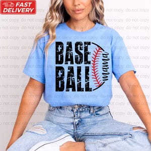 A woman wearing a blue t-shirt with the text "BASEBALL" printed on it, sitting on the ground.
