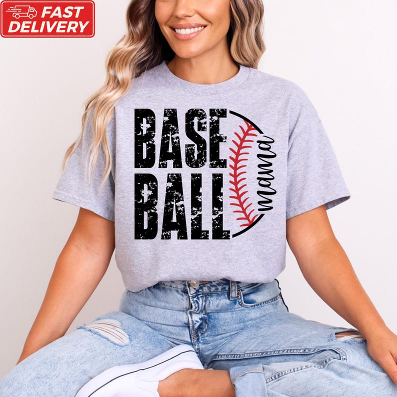 A woman wearing a grey t-shirt with the text "BASE BALL" printed on it, sitting on the floor with her legs crossed.