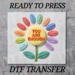 May include: A DTF transfer design featuring a flower with the words "YOU ARE ENOUGH" in the center. The flower's petals display positive affirmations like "BRAVE," "BOLD," and "STRONG." The text "READY TO PRESS" and "DTF TRANSFER" are also present.