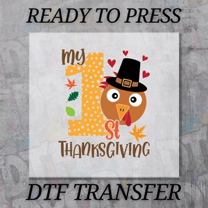 May include: A DTF transfer design with the text "READY TO PRESS" and "DTF TRANSFER". The design features a cartoon turkey wearing a pilgrim hat, the number "1" in orange with white polka dots, and the words "my 1st Thanksgiving".