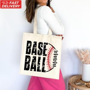 A woman is standing next to a white wall, carrying a tote bag with the text "BASE BALL" printed on it.