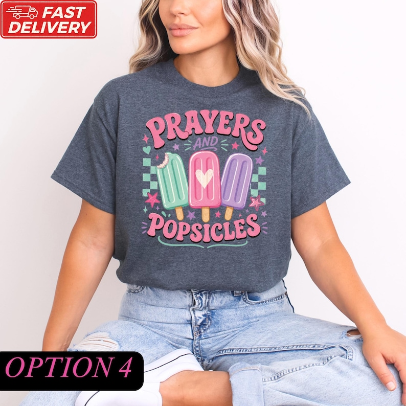 A woman wearing a gray t-shirt with a graphic design of three popsicles and the text "Prayers and Popsicles" printed on it.