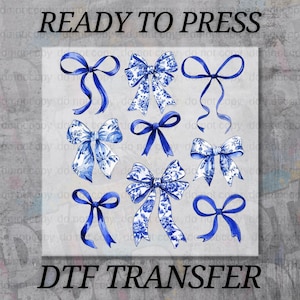 May include: A DTF transfer design featuring nine blue bows in various styles. Some bows have a floral pattern, while others are solid. The words "READY TO PRESS" and "DTF TRANSFER" are printed in black.