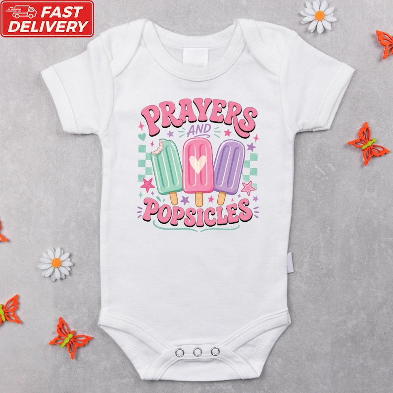 A white baby onesie with a colorful graphic design featuring three popsicles and the text "Prayers and Popsicles" printed on it.