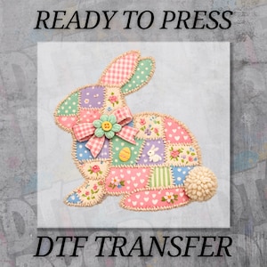 May include: A colorful patchwork bunny design with a pink bow and flower embellishment. The bunny is made of various patterned fabrics, including polka dots, gingham, and floral prints. The text "READY TO PRESS" and "DTF TRANSFER" are displayed.