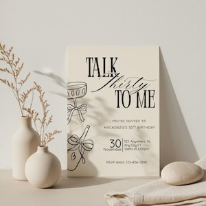 May include: A cream-colored invitation card with the text "TALK Thirty TO ME" in black script. The card includes event details and illustrations of a champagne glass and bottle. Two white vases with dried plants are on the left.