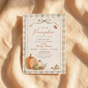 Puede incluir: Una tarjeta de invitación rectangular para baby shower con un borde de cuadros verde salvia, una ilustración en acuarela de calabazas y un lazo decorativo. El texto dice: A LITTLE Pumpkin IS ON ITS WAY PLEASE JOIN US FOR A BABY SHOWER HONORING EMILY JOHNSON.