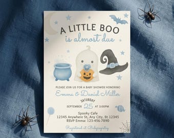 Może przedstawiać: Prostokątne zaproszenie na baby shower z kremowym tłem oraz niebieskim i czarnym tekstem o treści A LITTLE BOO is almost due. Ilustracje przedstawiają duszka ze smoczkiem, kociołek, kapelusz czarownicy, gwiazdki oraz księżyc.