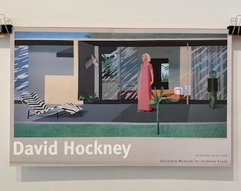 May include: A poster featuring a David Hockney artwork. The image depicts a modernist building with a woman in a pink dress. A chaise lounge with black and white stripes is in the foreground. The poster is held by black binder clips.