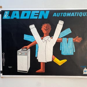Può includere: Poster vintage con la scritta "LADEN AUTOMATIQUE" in blu e bianco. Il poster presenta un personaggio dei cartoni animati con una camicia bianca, stivali gialli e asciugamani blu. Una lavatrice è a sinistra.