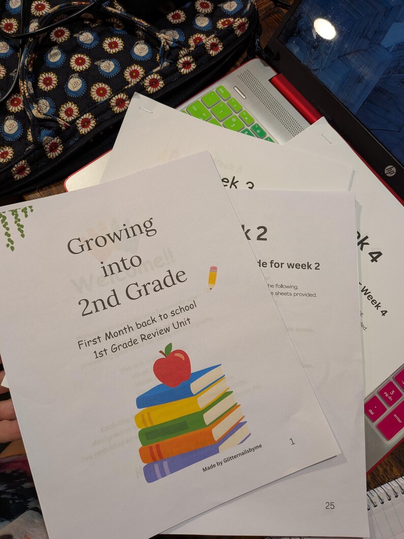 Peut inclure: Une pile de feuilles de travail &eacute;ducatives blanches intitul&eacute;es Growing into 2nd Grade First Month back to school 1st Grade Review Unit. La page de couverture pr&eacute;sente un graphique d'une pomme rouge sur une pile de livres bleu, jaune, vert et orange.