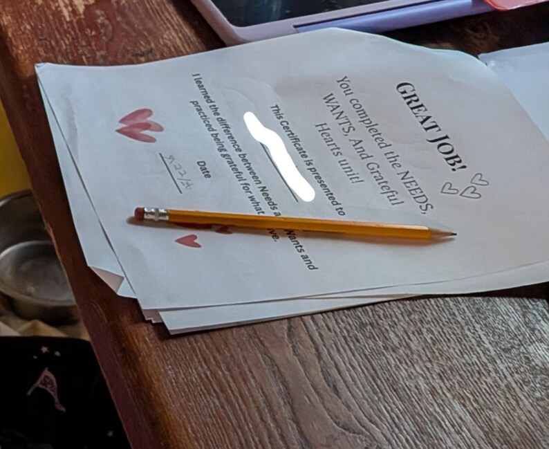 Może przedstawiać: Biały certyfikat z tytułem GREAT JOB! You completed the NEEDS, WANTS, And Grateful Hearts unit! Zawiera miejsce na datę, wydrukowane oświadczenie o wdzięczności oraz ilustracje czerwonych serc. Na papierze leży ż&oacute;łty oł&oacute;wek z drewna.