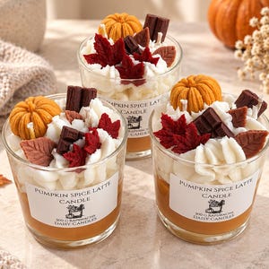 Peut inclure: Trois bougies en verre étiquetées Pumpkin Spice Latte Candle 300g. Chacune présente de la cire blanche façon chantilly, surmontée de petites citrouilles en cire, de carrés chocolatés marron foncé et de feuilles d'érable en cire rouge et marron.
