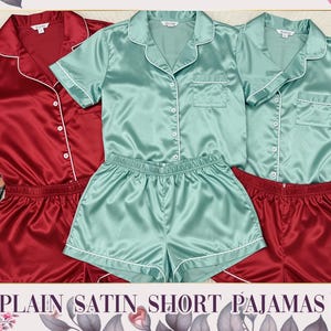 Può includere: Pigiama corto in raso rosso e verde acqua. I set includono una camicia a maniche corte con bottoni e pantaloncini abbinati, rifiniti con profili bianchi. L'immagine mostra anche palette di trucchi e il testo "PLAIN SATIN SHORT PAJAMAS".