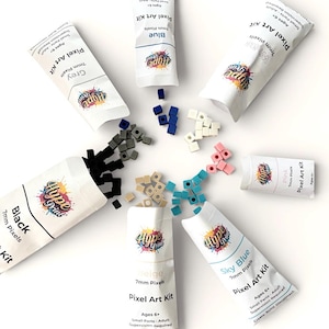 Pode incluir: Uma coleção de Kits de Arte Pixel em várias cores, incluindo preto, cinza, branco, azul, rosa, bege e azul celeste. Cada kit contém pixels de 7 mm e é projetado para crianças a partir de 6 anos. Os kits são embalados em tubos brancos com o logotipo "Hype Print".