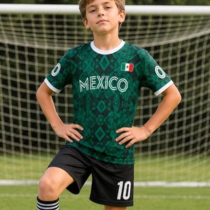 May include: A green soccer jersey with a geometric pattern and the word "MEXICO" in white. The jersey has white trim and a small Mexican flag. The shorts are black with the number 10 in white. The socks are black with white stripes.