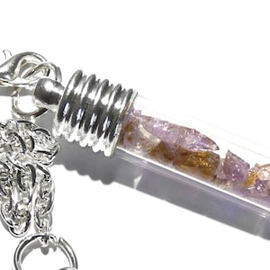 May include: Silver chain necklace with a glass vial pendant containing small purple and brown crystals.