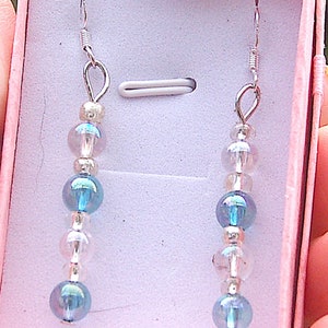 May include: A pair of silver earrings with blue and clear iridescent beads in a pink box.