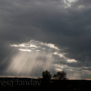 Puede incluir: Un cielo oscuro y tormentoso con un solo rayo de sol que atraviesa las nubes. Los rayos del sol son visibles como un haz de luz blanca brillante.