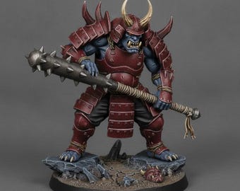 May include: A blue-skinned ogre figurine wearing dark red samurai armour with a horned helmet. The figure holds a large, spiked metal club in both hands. It stands on a rocky base with a small, discarded red mask lying on the ground nearby.