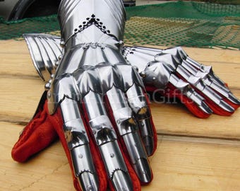 May include: A pair of polished steel gauntlets with articulated fingers and a red leather interior. The gauntlets are designed with overlapping plates for flexibility and protection, and are likely part of a suit of armor.