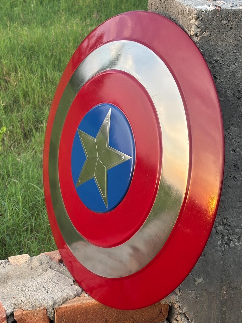 K&ouml;nnte beinhalten: Ein runder Schild mit einem roten Au&szlig;enring, einem silbernen Mittelring und einer blauen Mitte. Ein goldener Stern befindet sich in der Mitte des blauen Kreises. Der Schild lehnt an einer Betonmauer.
