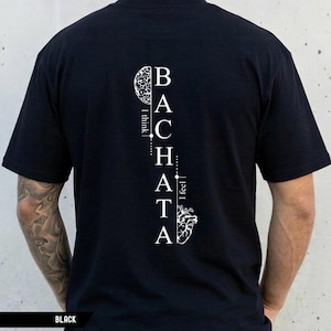 Può includere: T-shirt nera con la parola "Bachata" in bianco, disposta verticalmente. Il design include una grafica del cervello in alto e una grafica del cuore in basso. Sono incluse anche le frasi "Penso" e "Sento".