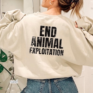 Può includere: Una felpa girocollo color sabbia con il testo nero dall'aspetto usurato END ANIMAL EXPLOITATION stampato sul retro. Il capo presenta maniche lunghe con polsini a coste e un colletto a coste, offrendo una vestibilità rilassata.