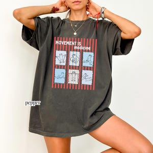 frogs doing therapy exercises on a Comfort Colors® t-shirt with “movement is medicine” text with stamps and lines in background design, printed on soft cotton shirt in various earthy tones