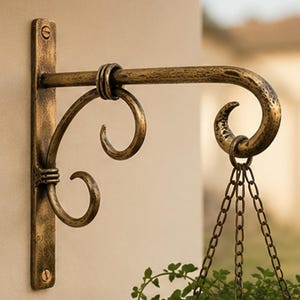 Puede incluir: Un soporte de pared para plantas con un acabado de bronce antiguo desgastado. El accesorio de metal cuenta con una placa de montaje vertical con dos orificios para tornillos, un brazo horizontal con extremo curvo y un soporte decorativo.
