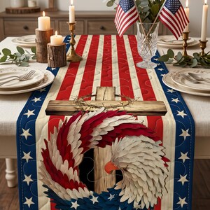 May include: A patriotic table runner featuring a design of the American flag with red and white stripes, blue borders with white stars, and a central image of a cross and eagle wreath. The table is set with candles and American flags.
