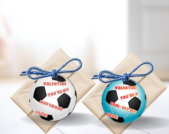 Pode incluir: Duas etiquetas de presente em forma de bola de futebol com laços de barbante azul. Uma etiqueta é branca com pentágonos pretos e diz "Valentine, você é meu amigo MVP". A outra é azul claro e diz "Valentine, você é um artilheiro".