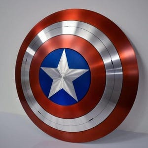 May include: A round shield with a red, silver, and blue color scheme. The shield features a large silver star in the center, set against a blue background. The outer ring is red, with silver bands separating the colors. A classic superhero accessory.