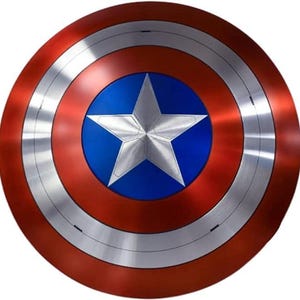 May include: A round shield with a red outer ring, a silver middle ring, and a blue center. A large, five-pointed silver star is centered on the blue circle. The shield has a metallic appearance.