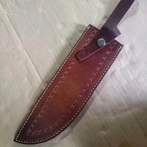 Peut inclure: Un &eacute;tui de couteau en cuir marron avec des coutures blanches et un motif en relief d&eacute;coratif. L'&eacute;tui est dot&eacute; d'une sangle avec une fermeture &agrave; bouton-pression. L'&eacute;tui est con&ccedil;u pour prot&eacute;ger la lame.