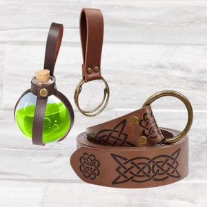May include: A selection of brown leather accessories. Includes a round glass bottle with green liquid, a key ring, and a belt with Celtic knot designs. The bottle has a cork stopper and leather straps.