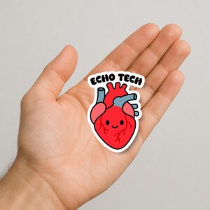 May include: A sticker featuring a cartoon heart with a smiling face, red body, blue veins, and pink chambers. The text "ECHO TECH" is above the heart. The sticker is held in a person's hand.