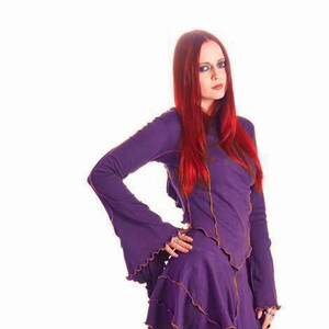 Peut inclure: Une femme aux longs cheveux roux portant une robe violette avec des bordures dorées et des bottes à plateforme noires.