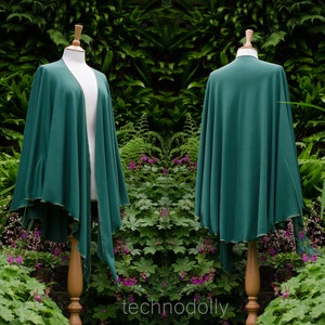 May include: A deep green hooded cloak with a gold trim. The cloak is draped over a mannequin and is shown from both the front and back.
