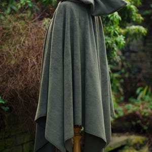 May include: A hooded cloak in a dark green color. The cloak is made of a soft, plush fabric and has a simple, elegant design.