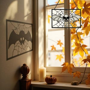 May include: A black metal Halloween decoration featuring a bat with a skull in the center, set against a spiderweb design. The decoration hangs in front of a window with autumn leaves. A shadow of a bat and web is cast on the wall.