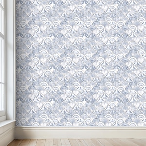 Pode incluir: Uma parede coberta com papel de parede com padr&atilde;o de conchas azuis e brancas. O papel de parede tem um design repetitivo em forma de leque, criando uma apar&ecirc;ncia texturizada. A sala tem um rodap&eacute; branco e um ch&atilde;o de madeira.