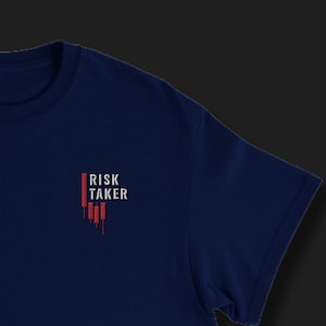 May include: A navy blue t-shirt with the words "RISK TAKER" in white and red. The design includes a graphic that looks like a stock market chart. The shirt has a crew neck and short sleeves.