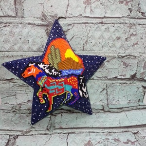 May include: A blue star-shaped beaded ornament with a colorful depiction of a horse and a sunset scene.