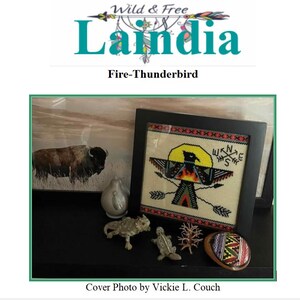 May include: A framed cross-stitch featuring a Thunderbird design with arrows and a compass rose. The image includes a bison painting, decorative figurines, and the text "Wild & Free Laindia Fire-Thunderbird".