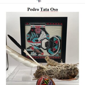 May include: A framed cross-stitch design with a black, white, red, and turquoise color scheme. The design features a geometric pattern with a central image of a pot. The frame is black with a white mat. There is a white feather, a small brown lizard, and a small, round, colorful clay pot in the image.