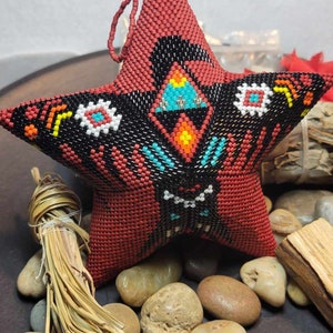 Könnte beinhalten: Ein roter, schwarzer, weißer, blauer und gelber Perlenstern mit geometrischem Muster. Der Stern hängt an einer türkisfarbenen Perle.